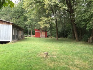 Kleine Wiese mit Blick vom Lärmschutzdamm zum Schupfen neben dem Fahnenmast